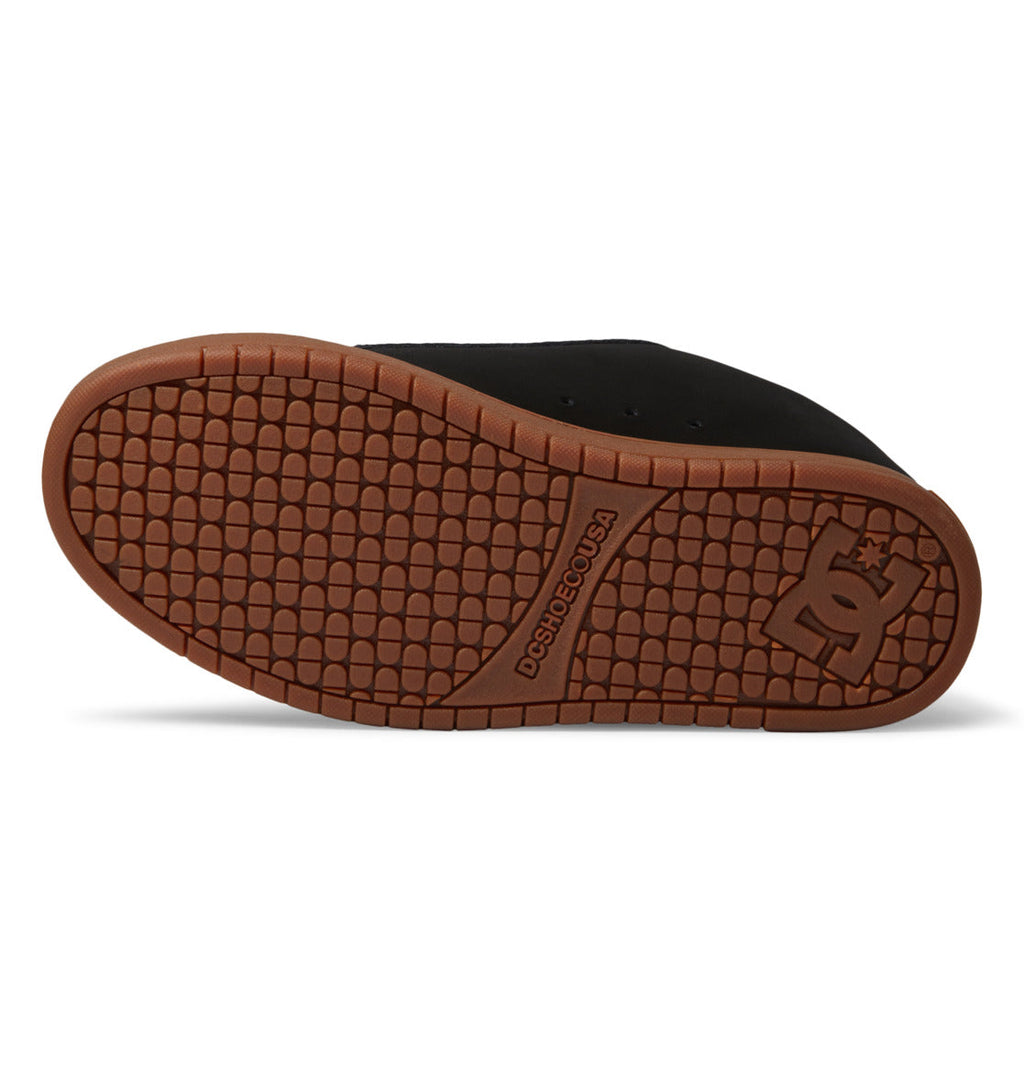 The image displays the brown rubber sole of the DC Shoes Men’s Court Graffik shoe in black, highlighting its textured grip pattern and the prominent DC Shoes logo near the heel. This iconic puffy silhouette delivers both comfort and signature style that make it instantly recognizable.
