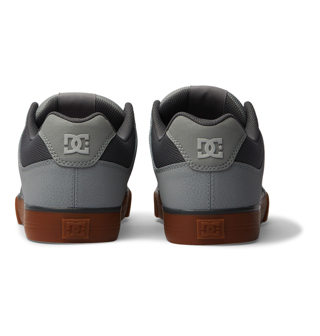 A pair of DC Shoes Men’s Pure Shoes in gray with brown rubber soles, viewed from the back. These versatile men’s shoes display the white DC logo on the heel of both shoes and are positioned side by side against a white background.