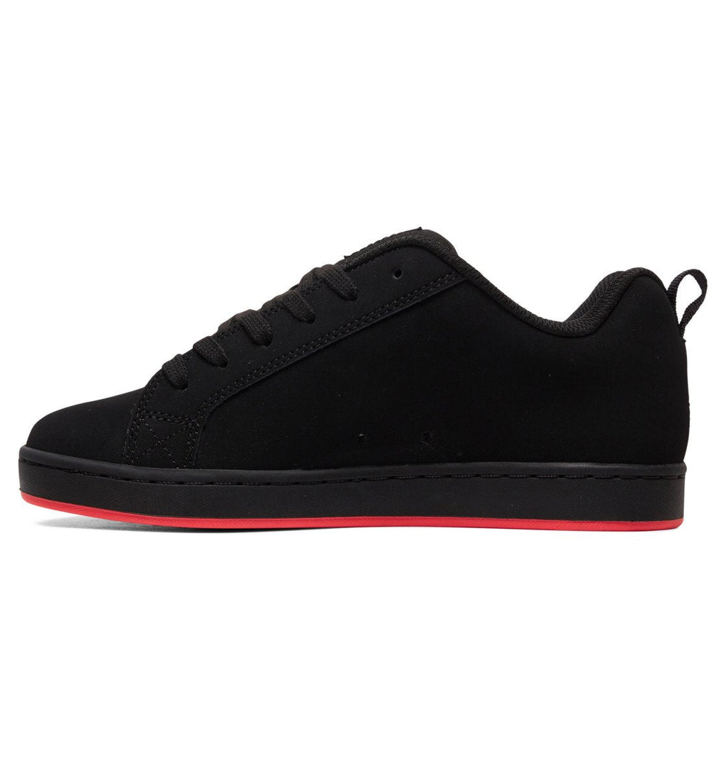 The Women’s Court Graffik Shoes by DC Shoes feature an all-black design with black laces, a black sole, and a slim red stripe along the bottom edge for a signature ’90s-inspired look. This women’s sneaker is displayed from the side against a white background.
