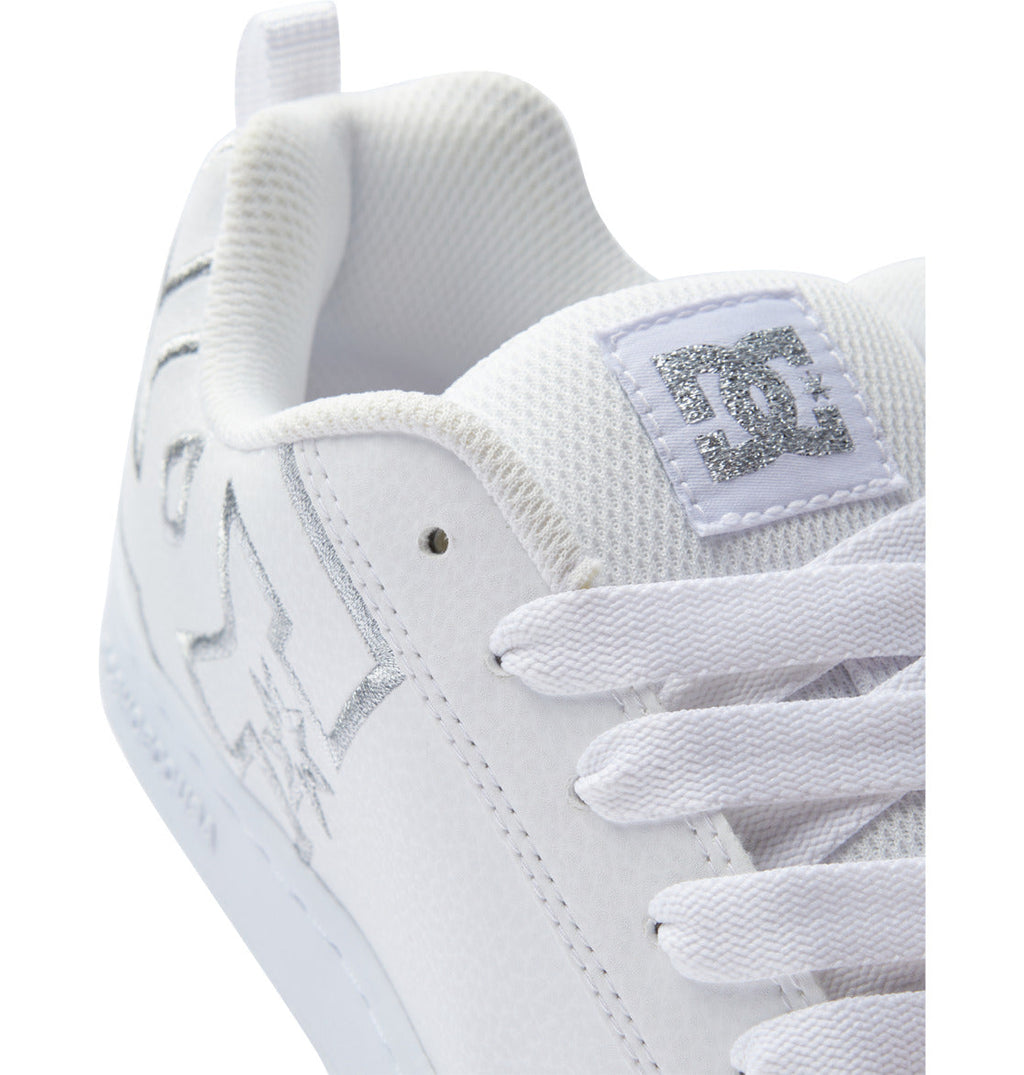 Close-up of the DC Shoes Women’s Court Graffik Shoes—a white chunky sneaker with white laces, silver stitching, and a textured white tongue adorned with a silver embroidered DC logo—an iconic nod to ‘90s style women’s sneakers.