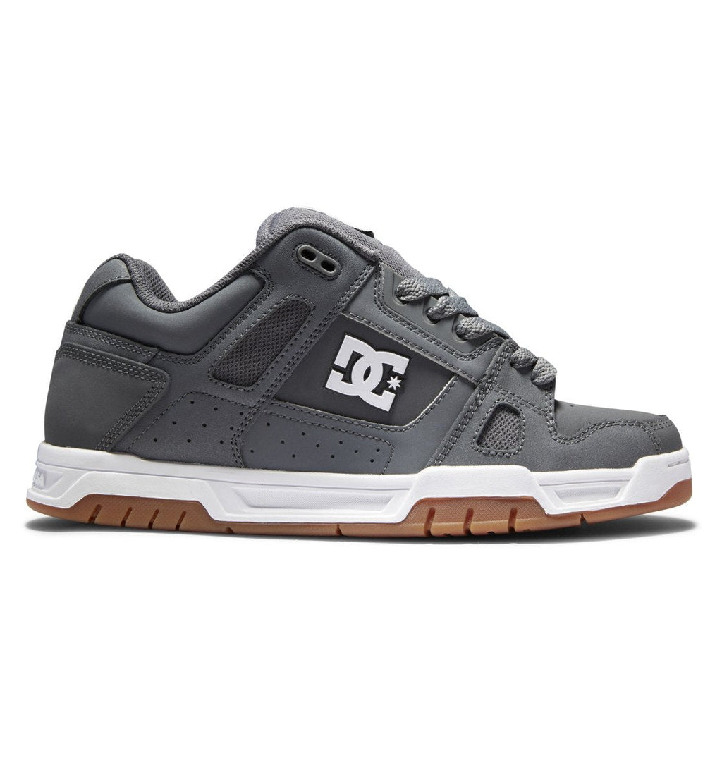Introducing the Men’s Stag Shoes by DC Shoes: these sneakers feature a sleek gray upper with a white sole and brown tread, highlighted by the signature DC logo in white on the side. The design includes gray laces, black trim accents, and a durable cupsole crafted for long-lasting wear.