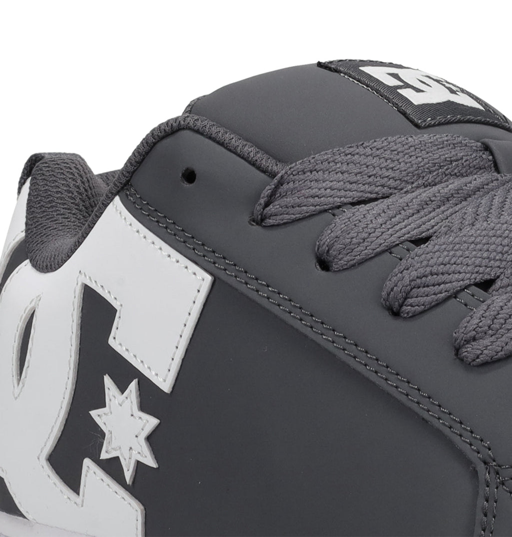 Close-up of the Men’s Court Graffik Shoes by DC Shoes, showcasing their signature chunky skate silhouette in grey with thick matching laces and a prominent white DC Shoes logo on the side. The detailed stitching and textured materials are clearly visible.