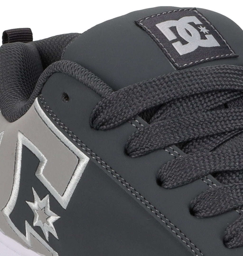 Close-up of a gray Men’s Court Graffik Special Edition Shoe by DC Shoes, featuring black laces and a silver DC Shoes logo design on the side, with detailed stitching, a puffy silhouette, and the signature DC Shoes logo on the tongue.