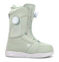 The Women’s Lotus Snowboard Boots by DC Shoes are shown against a plain white background, featuring a light green design with a white sole, a side round tightening dial, and subtle panel stitching for enhanced comfort and support.