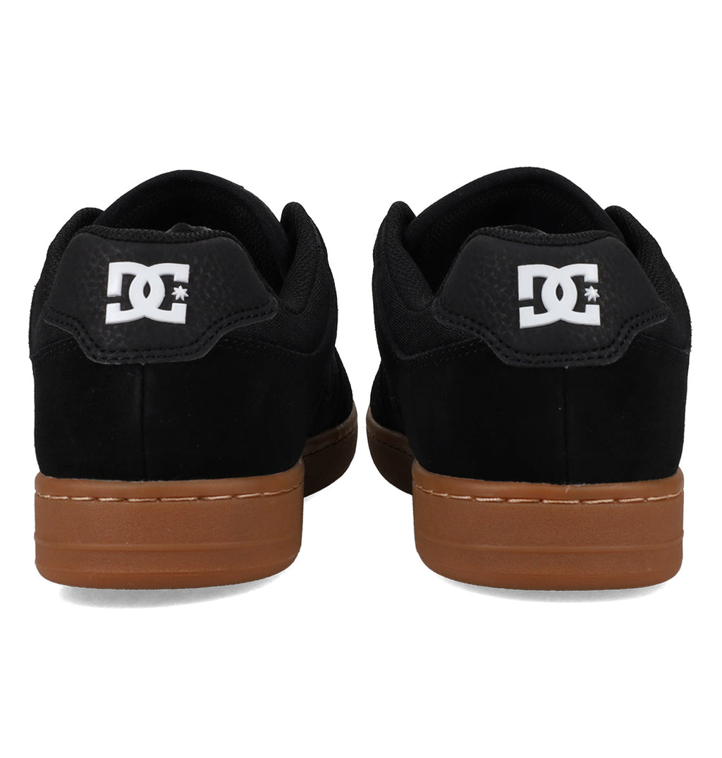 A pair of Men’s Manteca 4 Shoes by DC Shoes in black with brown soles, shown from the back to highlight the white DC logo on each heel, designed for modern comfort and everyday wear.