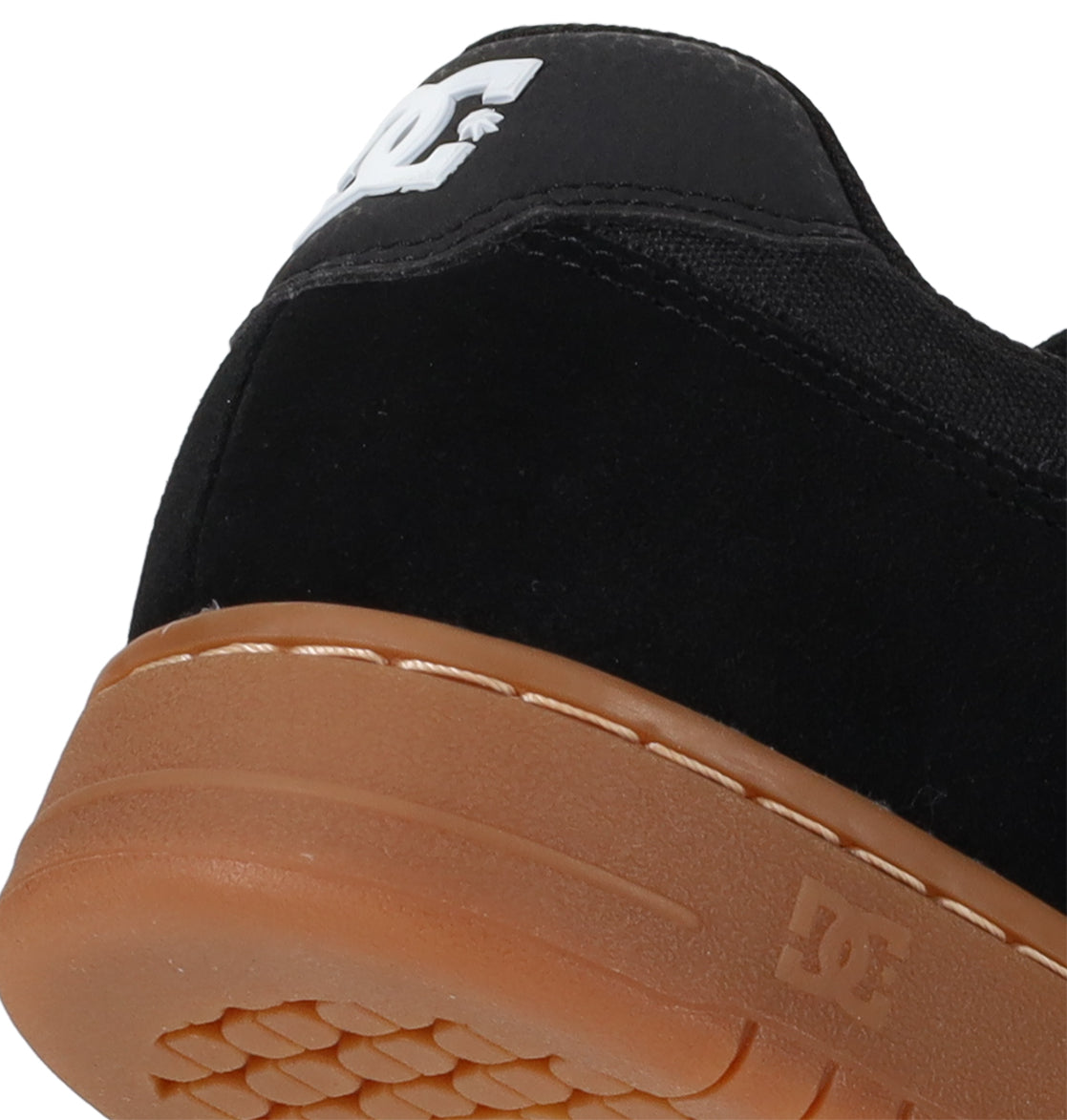 Close-up of the heel of a black Men’s Manteca 4 Shoe by DC Shoes, featuring a brown rubber sole. The white DC Shoes logo stands out on the back, highlighting the modern comfort and style these skate shoes are known for.