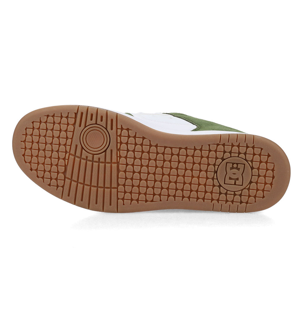 The image displays the tan-colored sole of the Men’s Manteca 4 Shoes by DC Shoes, featuring a textured, grid-like tread pattern, a circular motif, and the signature DC Manteca logo—highlighting its performance-oriented design. The upper section of the shoe is green and white.