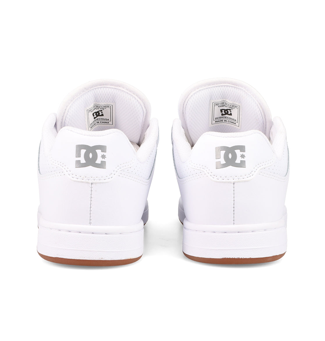 A pair of white DC Shoes Women's Manteca 4 is shown from the back, featuring a gray DC logo on the heel, white soles, and brown edges—highlighting the performance-driven design.