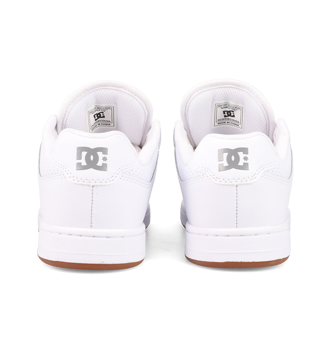 A pair of white DC Shoes Women’s Manteca 4 viewed from the back, displaying the DC logo on each heel, complemented by white midsoles and brown outsoles—showcasing a performance-oriented design ideal for skate enthusiasts.
