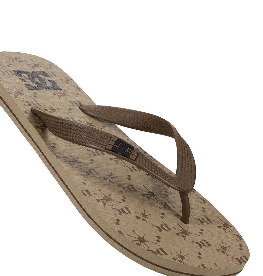 The Men's Spray Graffik Slides by DC Shoes feature a brown textured strap and a beige patterned sole with starburst designs and the DC logo—perfect slides to relax in after a skate session.