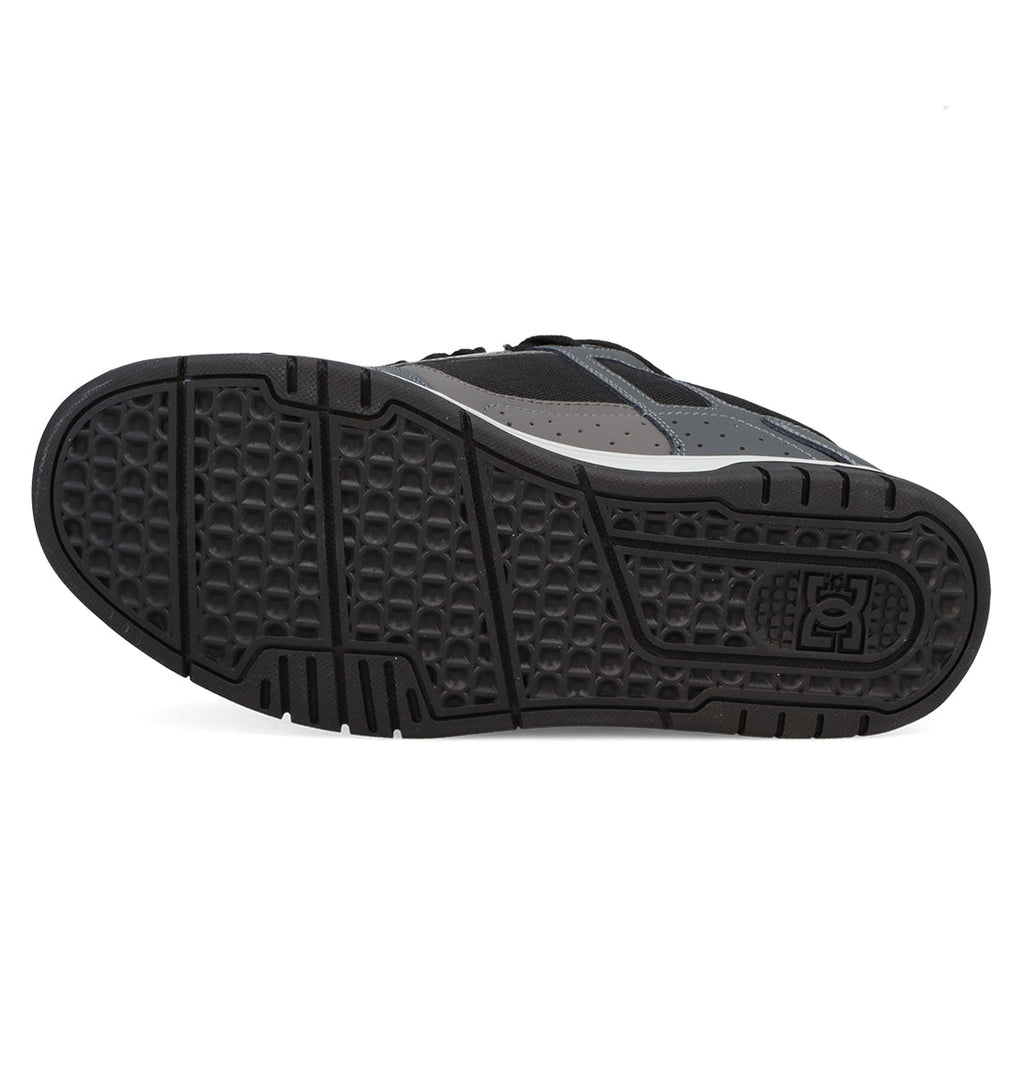 The image features the black rubber sole of the Men’s Stag Shoes by DC Shoes, showcasing a textured pattern with the DC Shoes logo near the heel and emphasizing its durable cupsole construction—a signature element appreciated in skate culture and characteristic of this model.