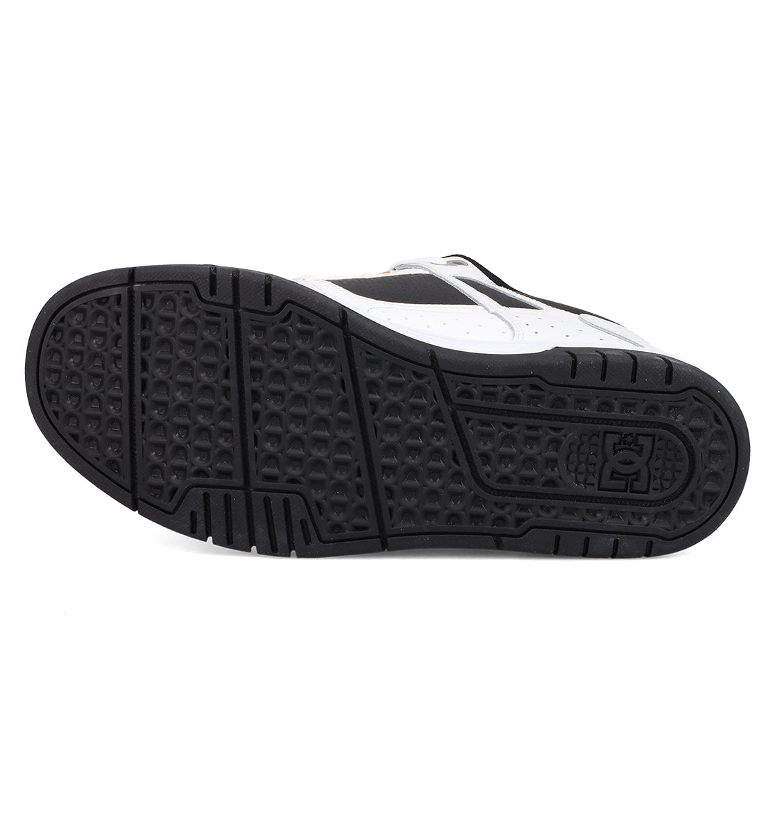 The image shows the black rubber outsole of DC Shoes Men's Stag Shoes, with geometric tread patterns, a grid-like texture, and a circular logo by the heel. The durable cupsole pairs with a white and black upper inspired by skate culture.