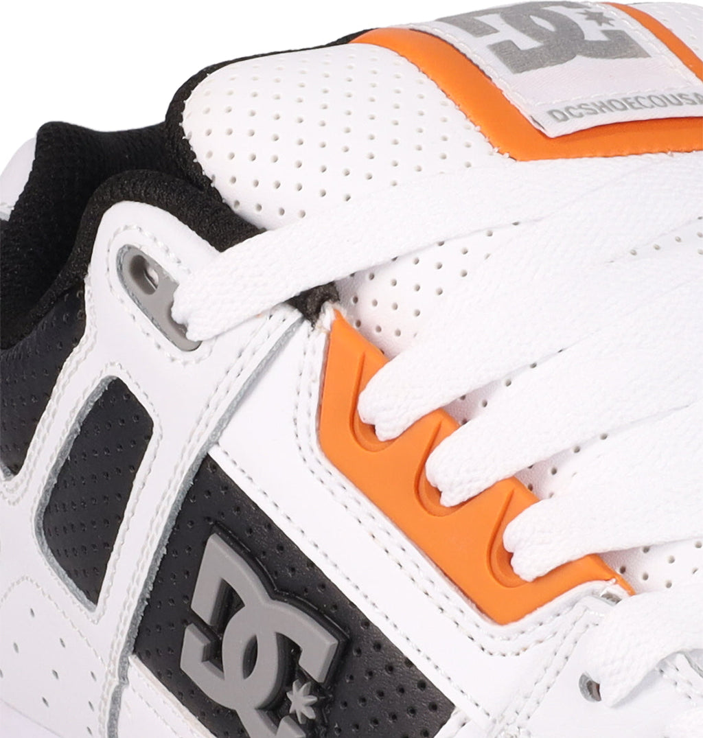 Close-up of the DC Shoes Men's Stag, a white sneaker with black and orange accents, featuring the DC logo on the side and a perforated tongue with label—skate-inspired style with a durable cupsole.
