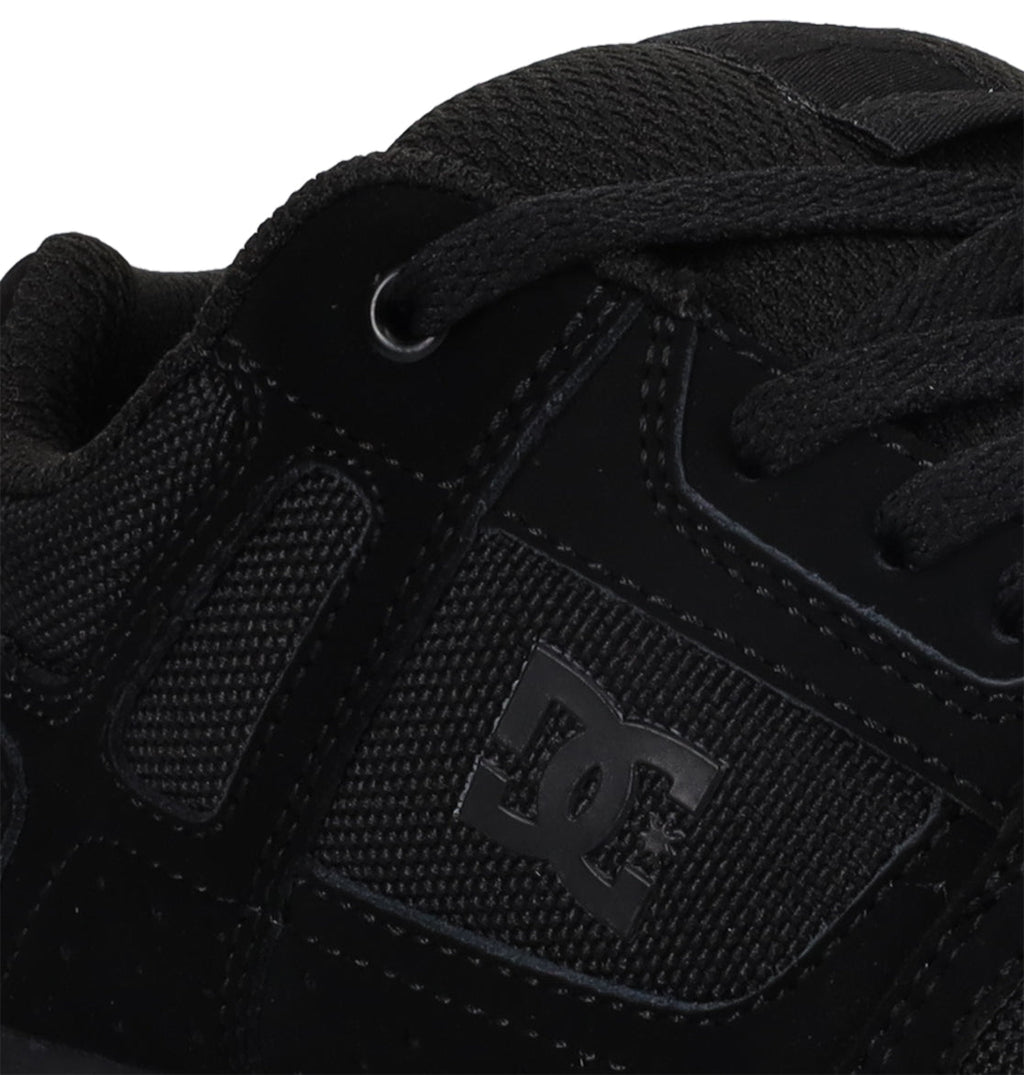 Close-up of a black Kids’ Stag Shoe by DC Shoes, featuring mesh and suede textures, detailed stitching, black laces, a durable cupsole, and the DC logo on the side.