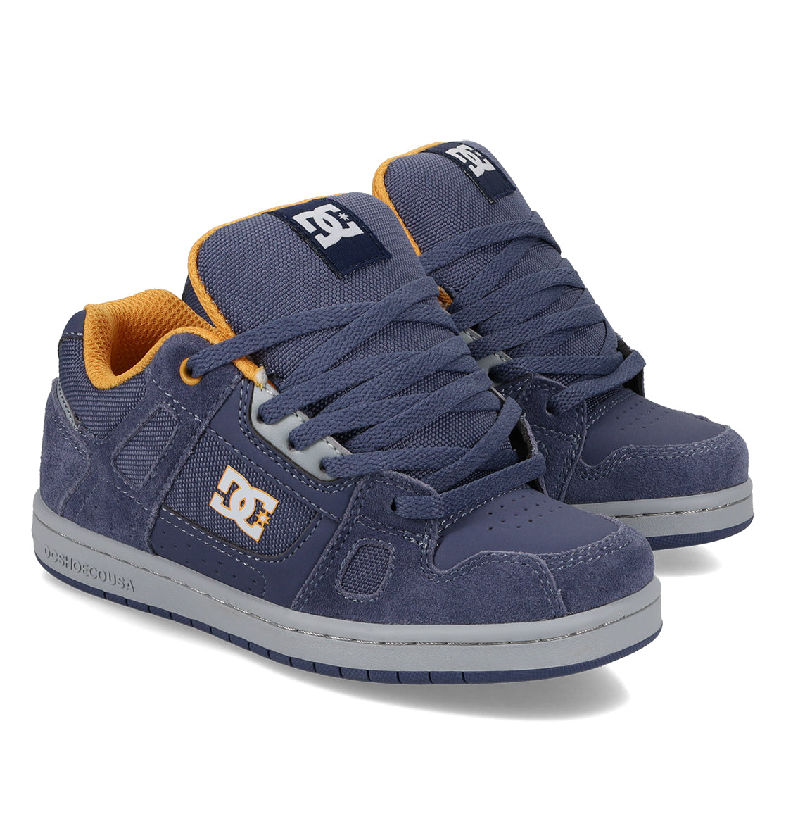 A pair of DC Shoes Kids’ Stag Shoes in navy blue, featuring orange inner lining, grey and white soles, and large navy laces. With a minimal silhouette and the iconic DC logo on the side, tongue, and heel, these vulc sneakers are perfect for everyday style and comfort.