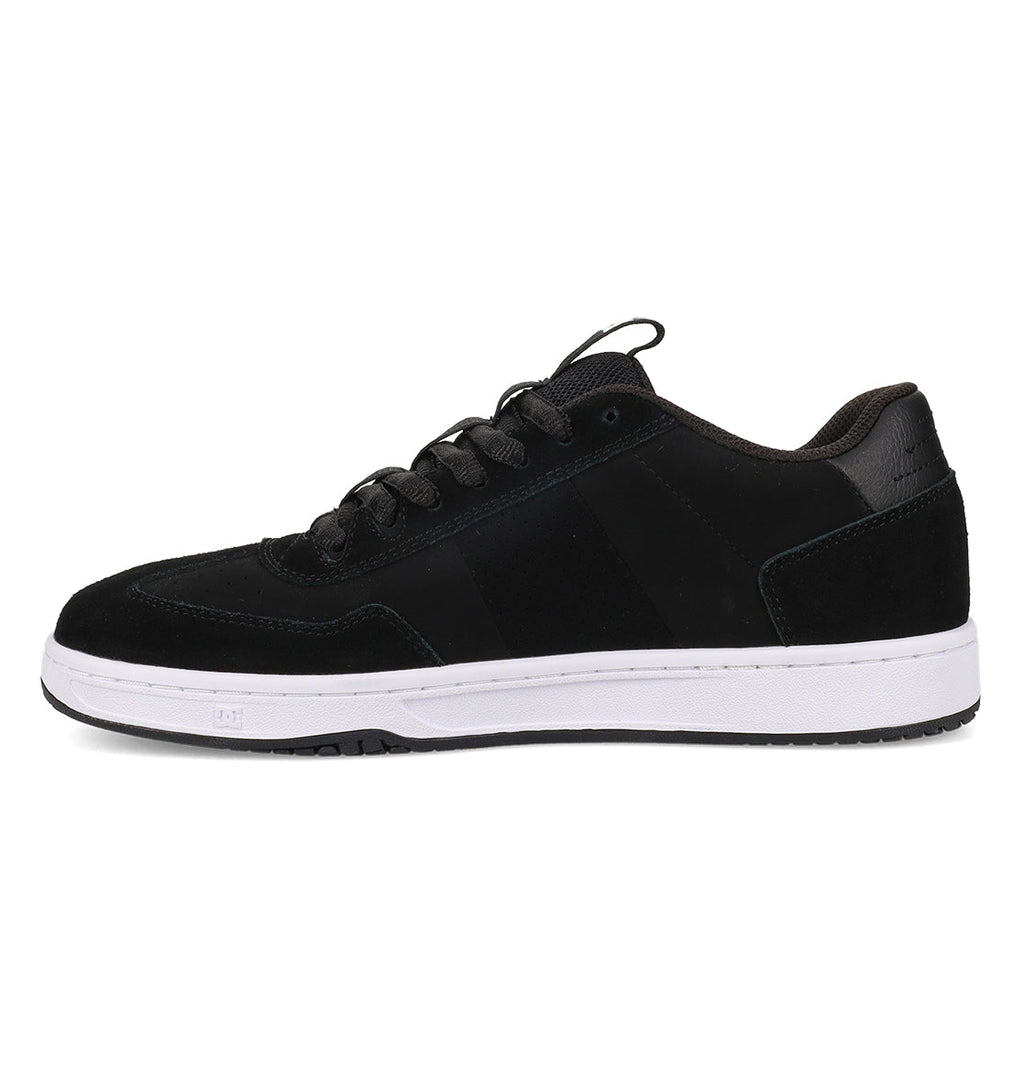 A side view of the Men’s Astrix Shoes by DC Shoes—a black low-top skate shoe featuring black laces and a white rubber sole—designed for superior board control, set against a white background.