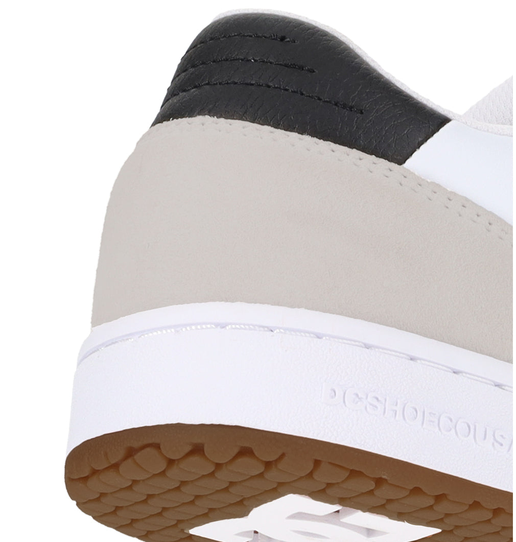 Close-up of the heel of the Men’s Astrix Shoes by DC Shoes, featuring a white sole, light gray suede upper, black textured heel detail, and gum brown tread—engineered for superior board control in street skateboarding. The DC Shoes brand name is subtly visible on the white midsole.