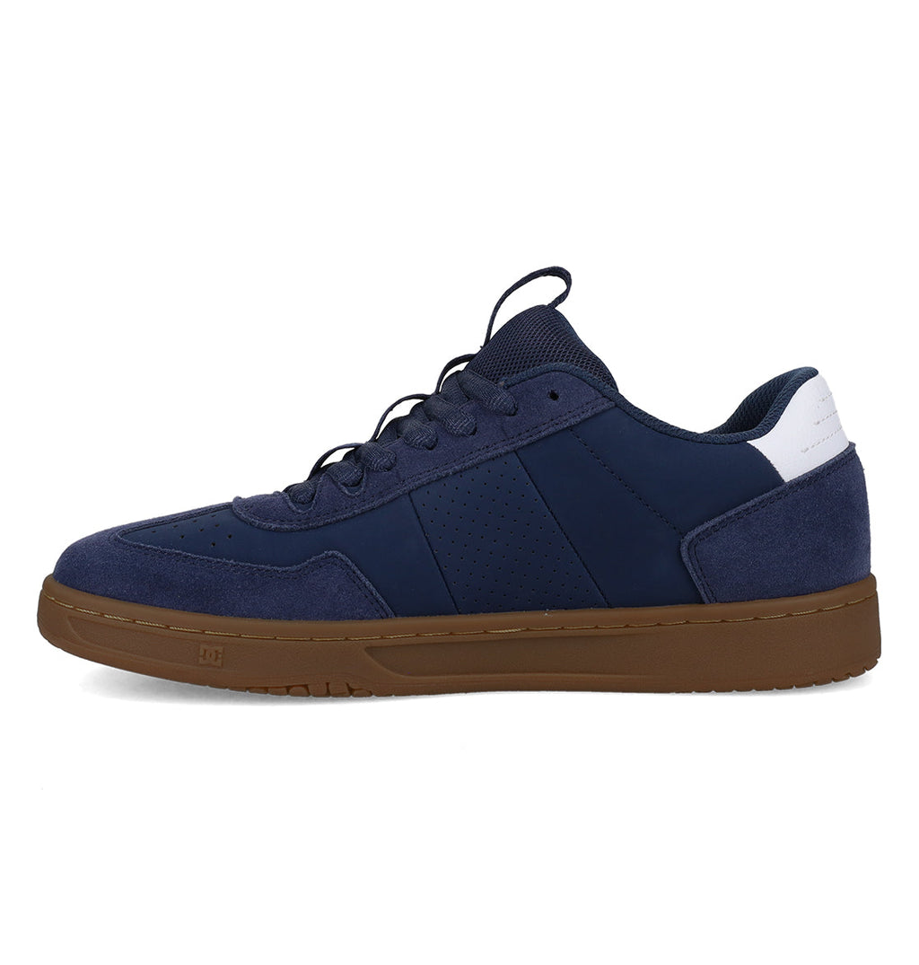 The Men’s Astrix Shoes by DC Shoes feature a navy blue design with suede and mesh panels, white detailing on the heel, black laces, and a brown rubber sole engineered for superior board control. The shoe is displayed in a left side profile against a white background.