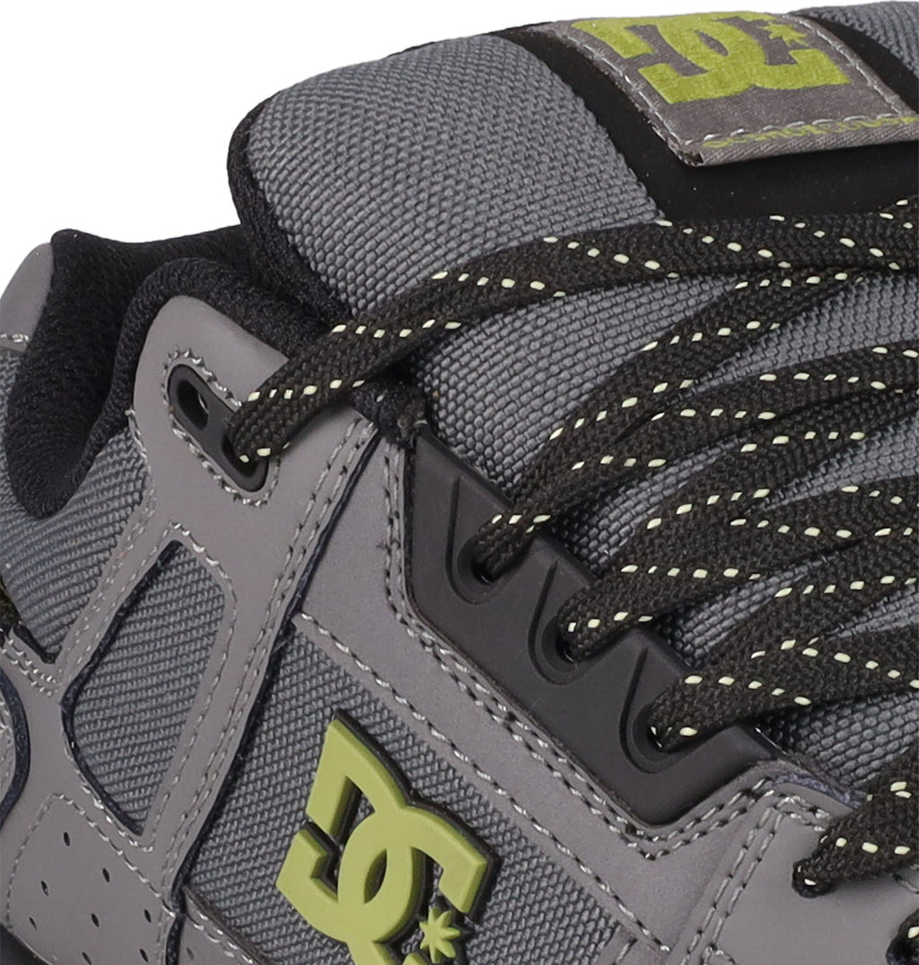 Close-up of DC Shoes Men's Stag Shoes in gray with black and yellow accents, featuring a standout yellow DC logo on the side, black eyelets, yellow-speckled laces, and a sturdy skate-inspired cupsole.