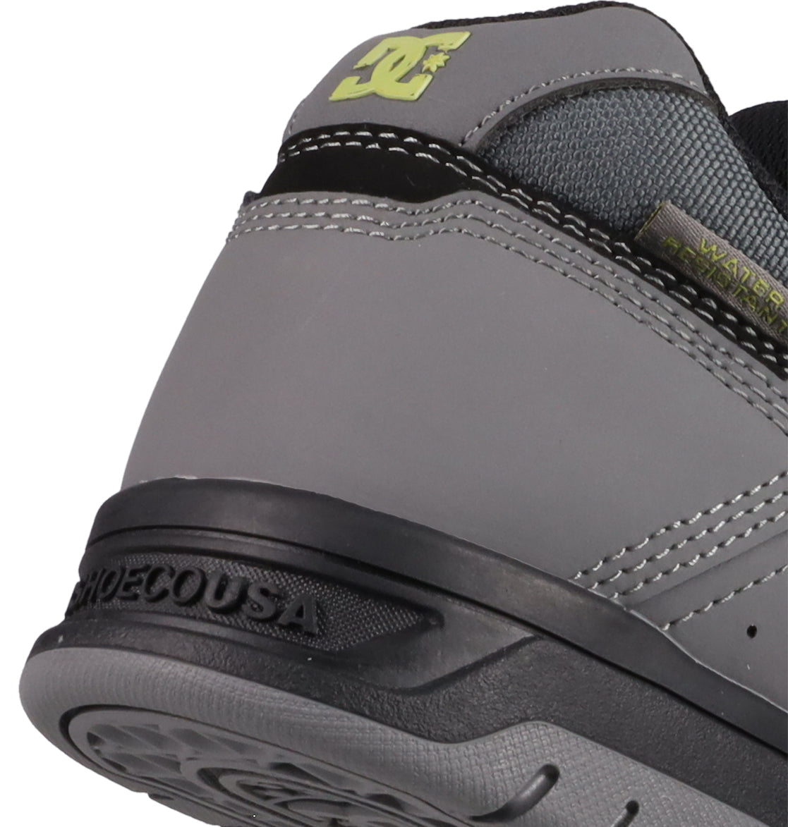 Close-up of the heel of DC Shoes Men's Stag, a gray sneaker with black and light green accents, visible stitching, durable cupsole, logo detailing, and a WATER RESISTANT tag—merging style and skate heritage.