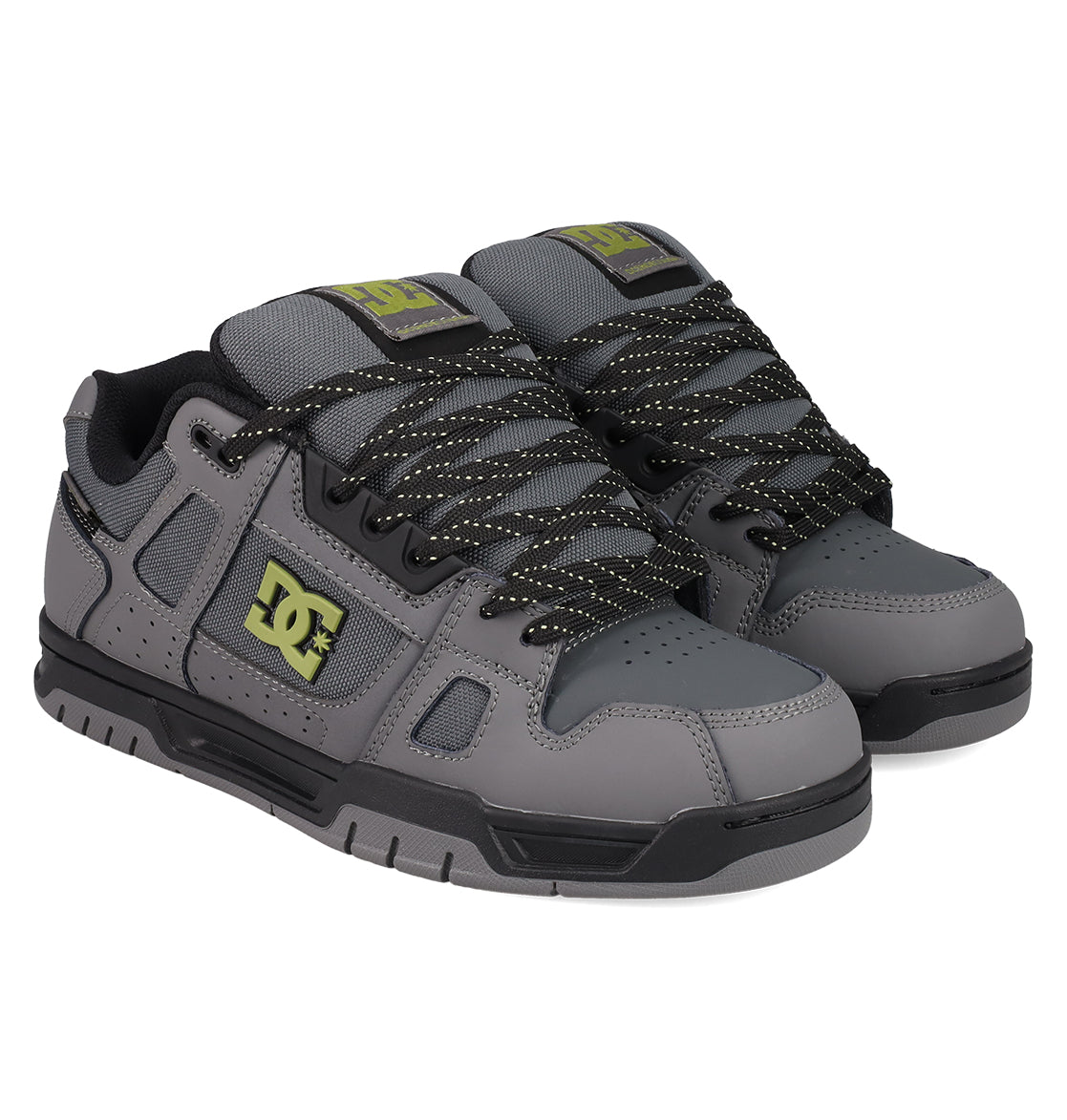 The DC Shoes Men's Stag Shoes feature a gray design with black detailing, black-and-white speckled laces, a durable cupsole, and yellow DC branding on the side, tongue, and heel tab—highlighting authentic skate style.