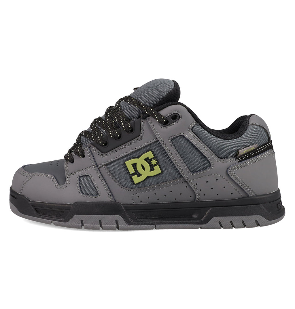 The DC Shoes Men's Stag Shoes feature a gray upper with black laces, black sole, yellow DC logo, padded tongue and collar, perforated details for breathability, and a durable cupsole inspired by skate culture.