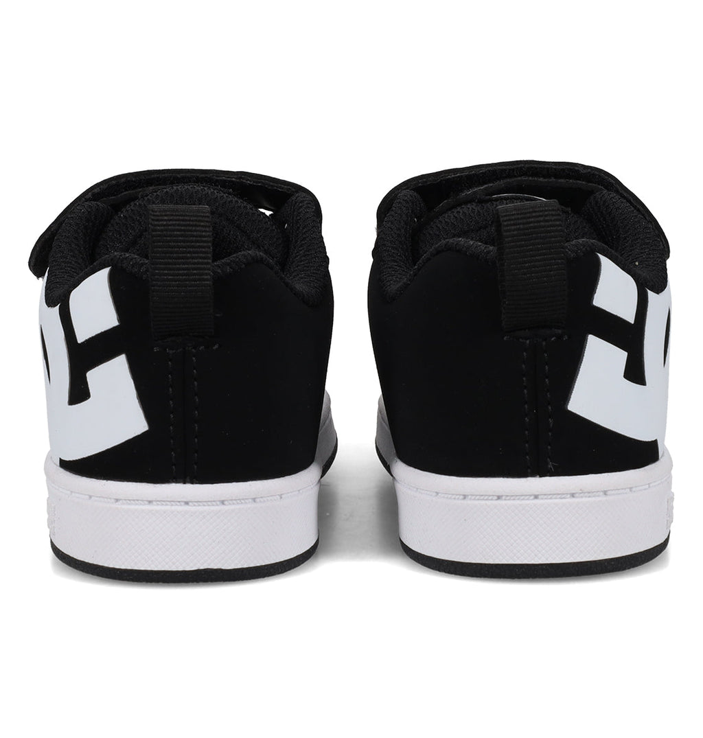 A pair of DC Shoes Kids’ Court Graffik Shoes – Toddler in black, viewed from the back. These sneakers feature a puffy, classic Court Graffik-inspired silhouette with thick white soles, bold white geometric designs on the heels, and black pull tabs at the top of the heel area.