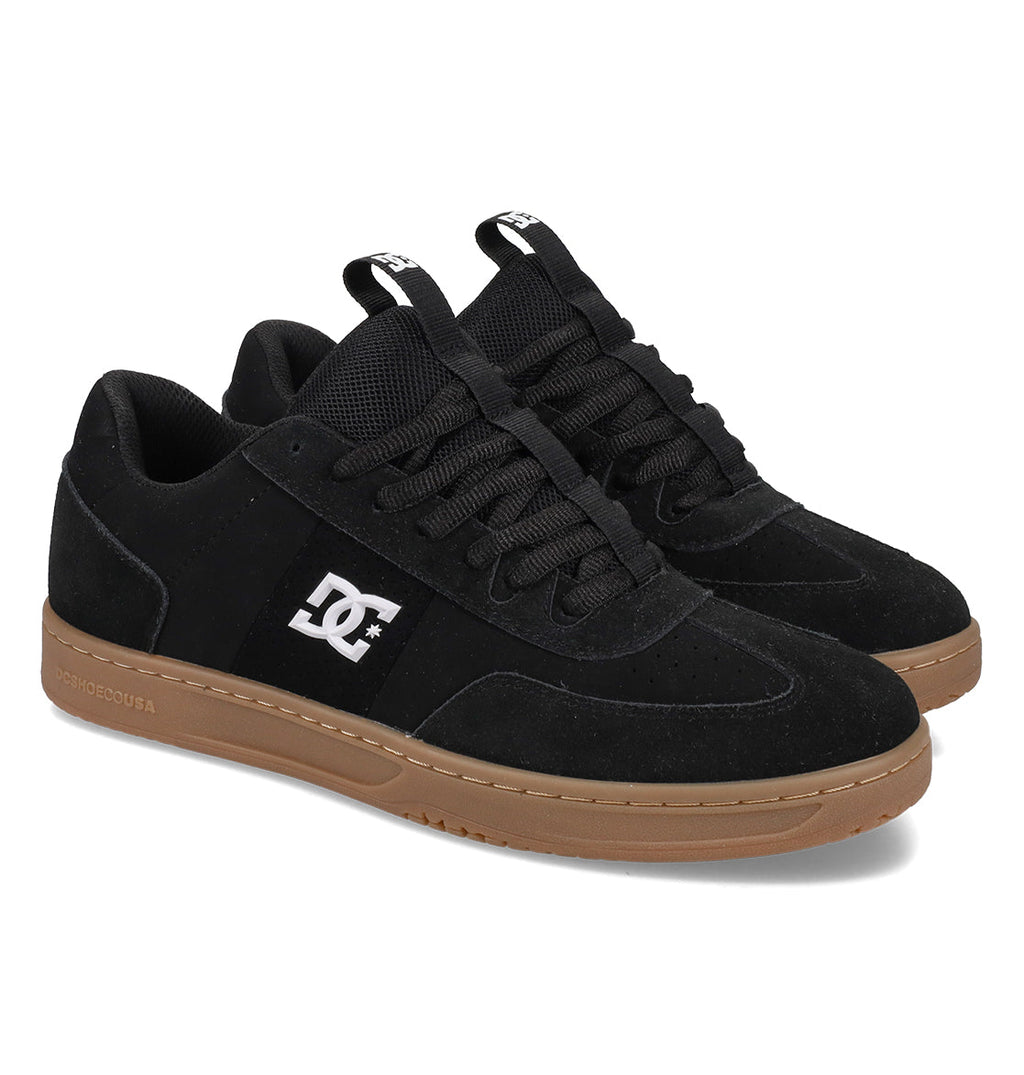 A pair of DC Shoes Men’s Astrix Shoes featuring black suede uppers, black laces, and brown rubber soles, accented with the signature white DC logo on the side—ideal for street skateboarding and engineered to provide outstanding board control.
