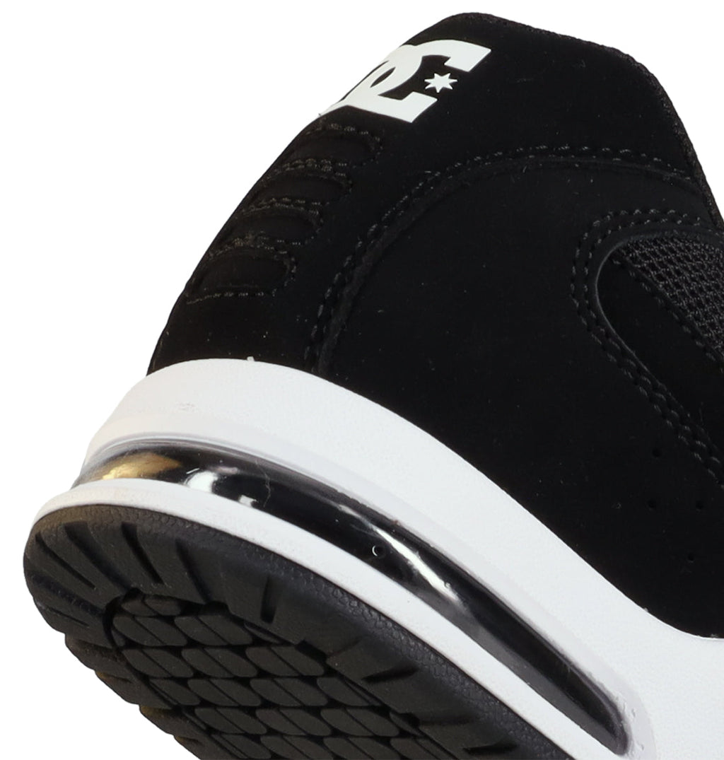 Close-up of the heel and sole of the Men’s AT-2 Shoes by DC Shoes, featuring a black upper with a white midsole, transparent air cushion for cushioned impact, and a partial white logo on the back. The tread pattern on the black outsole is also visible, highlighting AEROTECH ventilation technology for breathable comfort throughout every step.