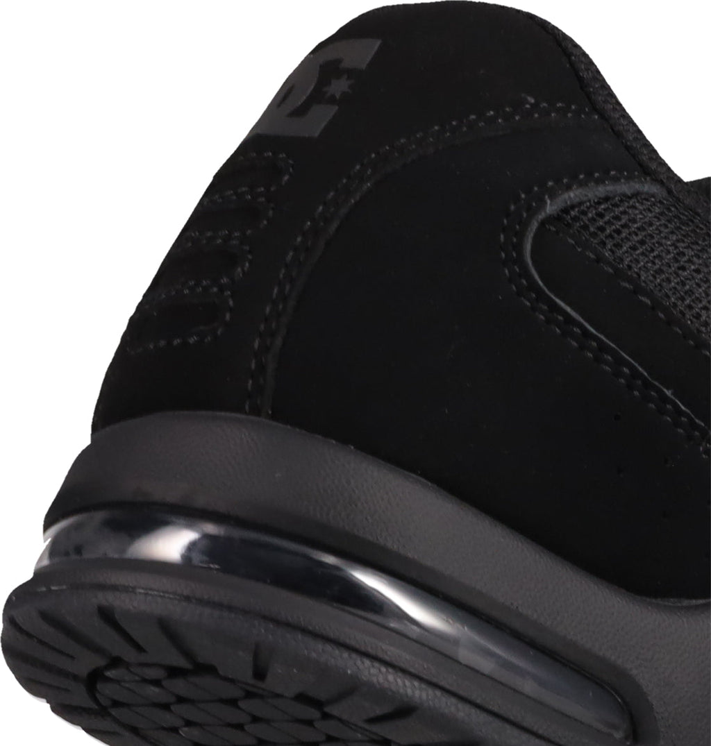 Close-up of the heel and sole of the black Men's AT-2 Shoes by DC Shoes, highlighting the textured airband outsole tread, visible air cushion in the sole, detailed stitching, and part of the logo on the upper.