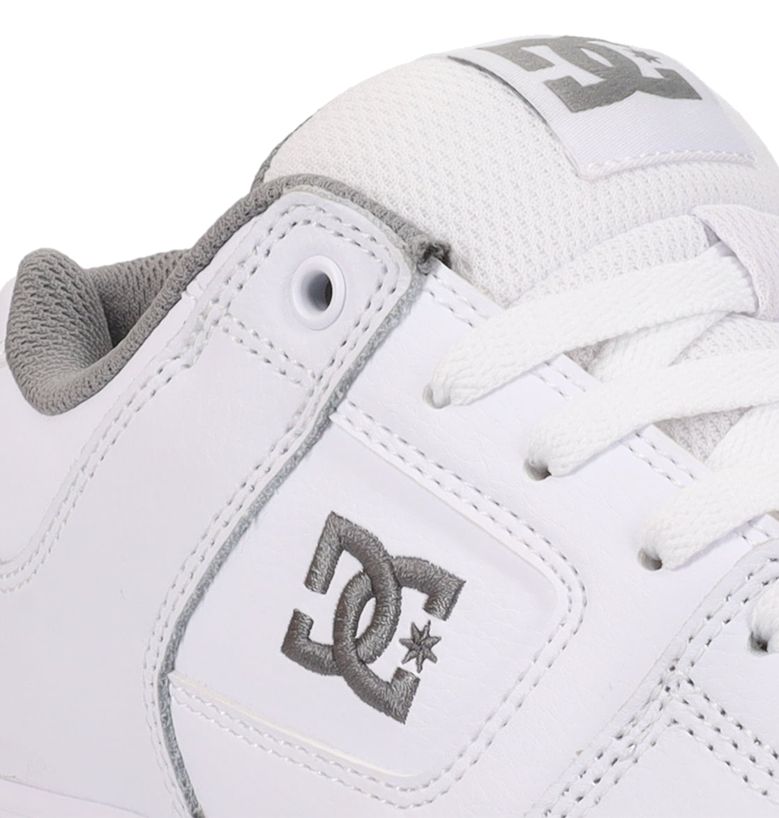 A detailed look at the Women’s Pure Shoes from DC Shoes showcases a white sneaker accented with gray, displaying the embroidered DC Shoes logo on the side and a printed logo on the tongue. The design features white laces and a padded gray interior, delivering lightweight cushioning for increased comfort and excellent impact absorption with each step.