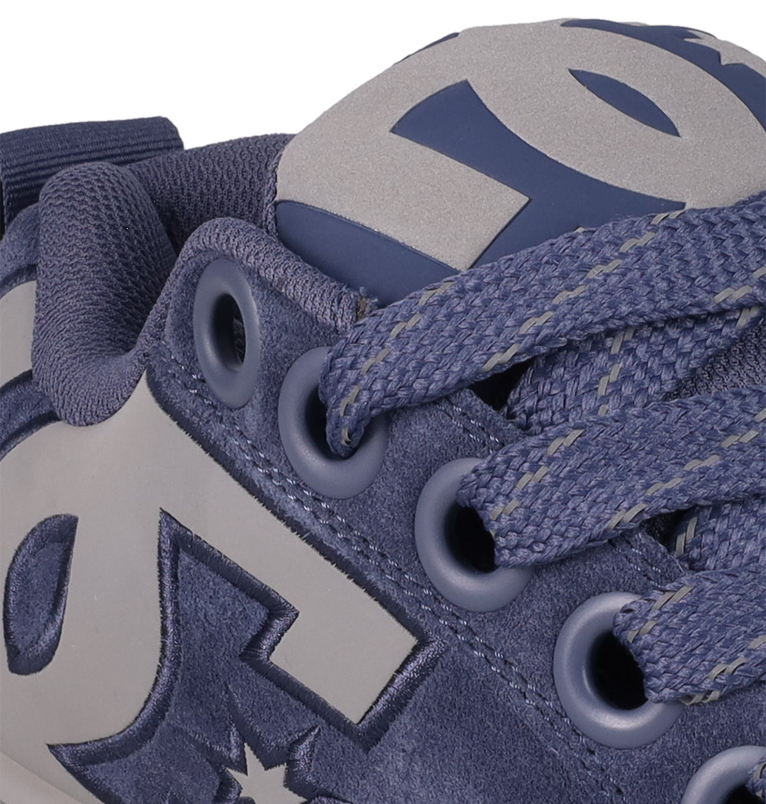 Close-up of DC Shoes Men's Court Graffik Shoes in blue with gray accents, puffy silhouette, suede and fabric materials. The laces, eyelets, and bold gray DC logo on the side and tongue stand out on this classic-inspired sneaker.
