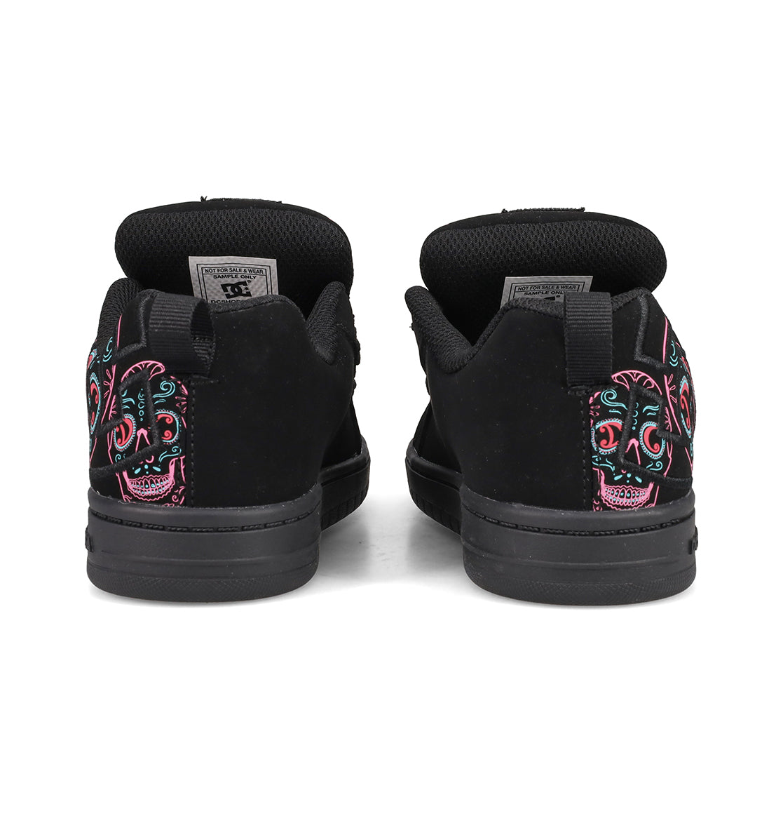 A pair of DC Shoes Kids’ Court Graffik Day Of The Dead sneakers, shown from the back, featuring colorful embroidered sugar skull designs on the heels. These black sneakers are inspired by Día de los Muertos and are part of the exclusive Day of the Dead Collection from DC Shoes.