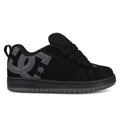 A side profile view of the DC Shoes Kids’ Court Graffik Beveled Special Edition features a black skate shoe with a puffy silhouette, thick laces, a large gray DC logo on the side, and a dark gray sole, displayed on a white background.