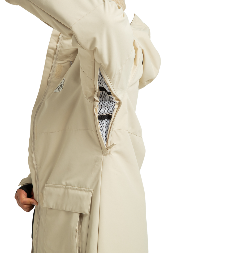 A person in a beige DC Shoes Women’s Cruiser Insulated Jacket displays a large zippered underarm vent with mesh lining. This recycled polyester jacket from DC Shoes features a flap pocket and a small side logo, merging practical weather defense technology with sustainable style.