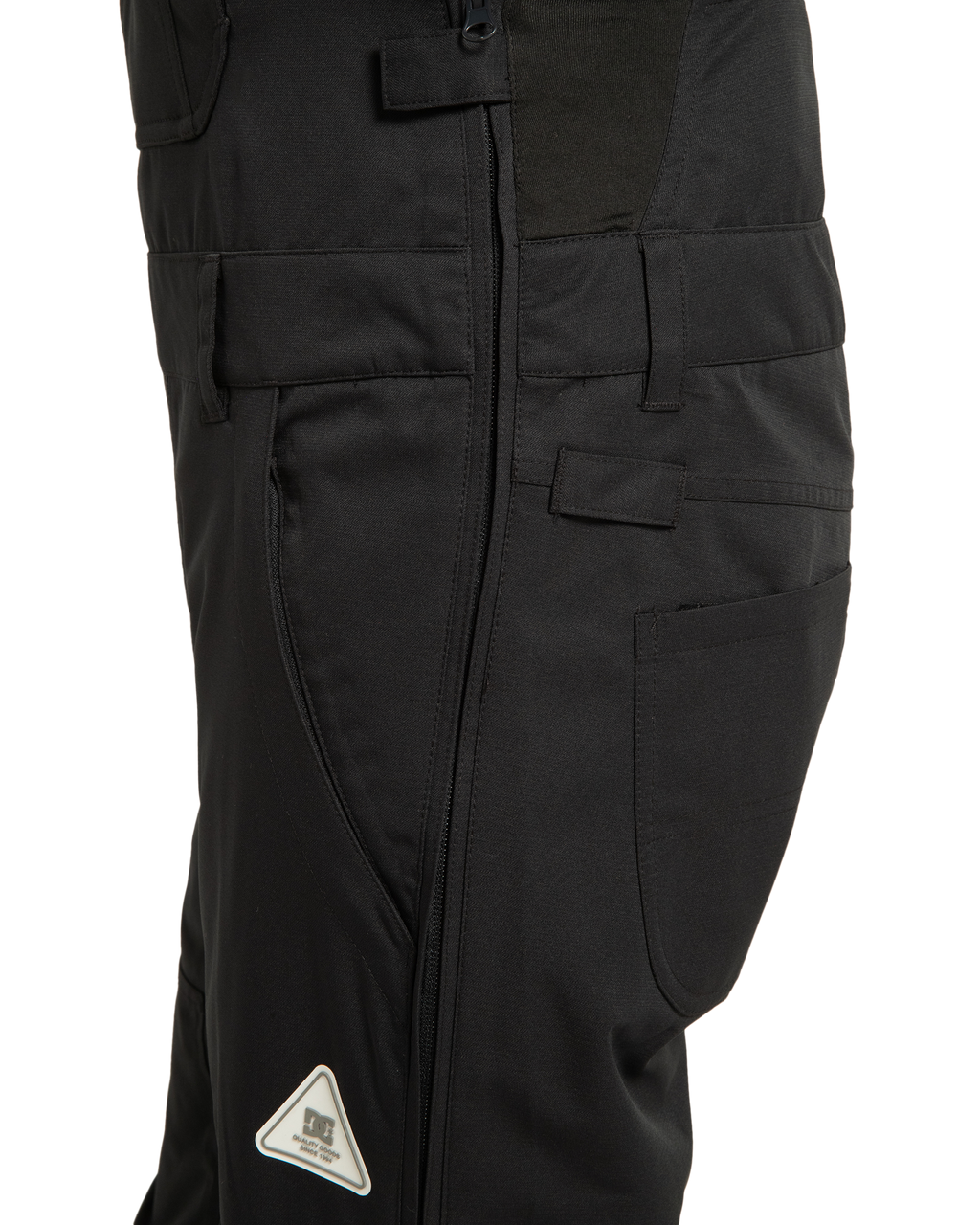 Close-up of the DC Shoes Women’s Crusade Shell Bib in black, featuring a side zipper, pockets, belt loops, and a small triangular reflective patch near the knee—making it an ideal choice for women’s adventure gear that delivers waterproof protection in any environment.