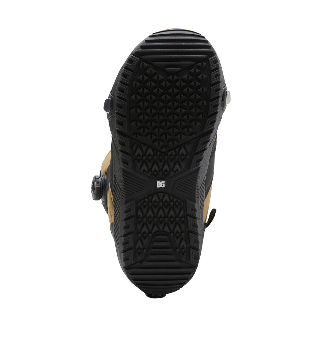 Sole view of a black and tan Men’s Judge Step On® Snowboard Boot featuring a textured rubber tread pattern and a round BOA Fit System dial on the side. The DC Shoes logo appears in the center of the sole, emphasizing key details from the DC Shoes Judge Step On® collection.