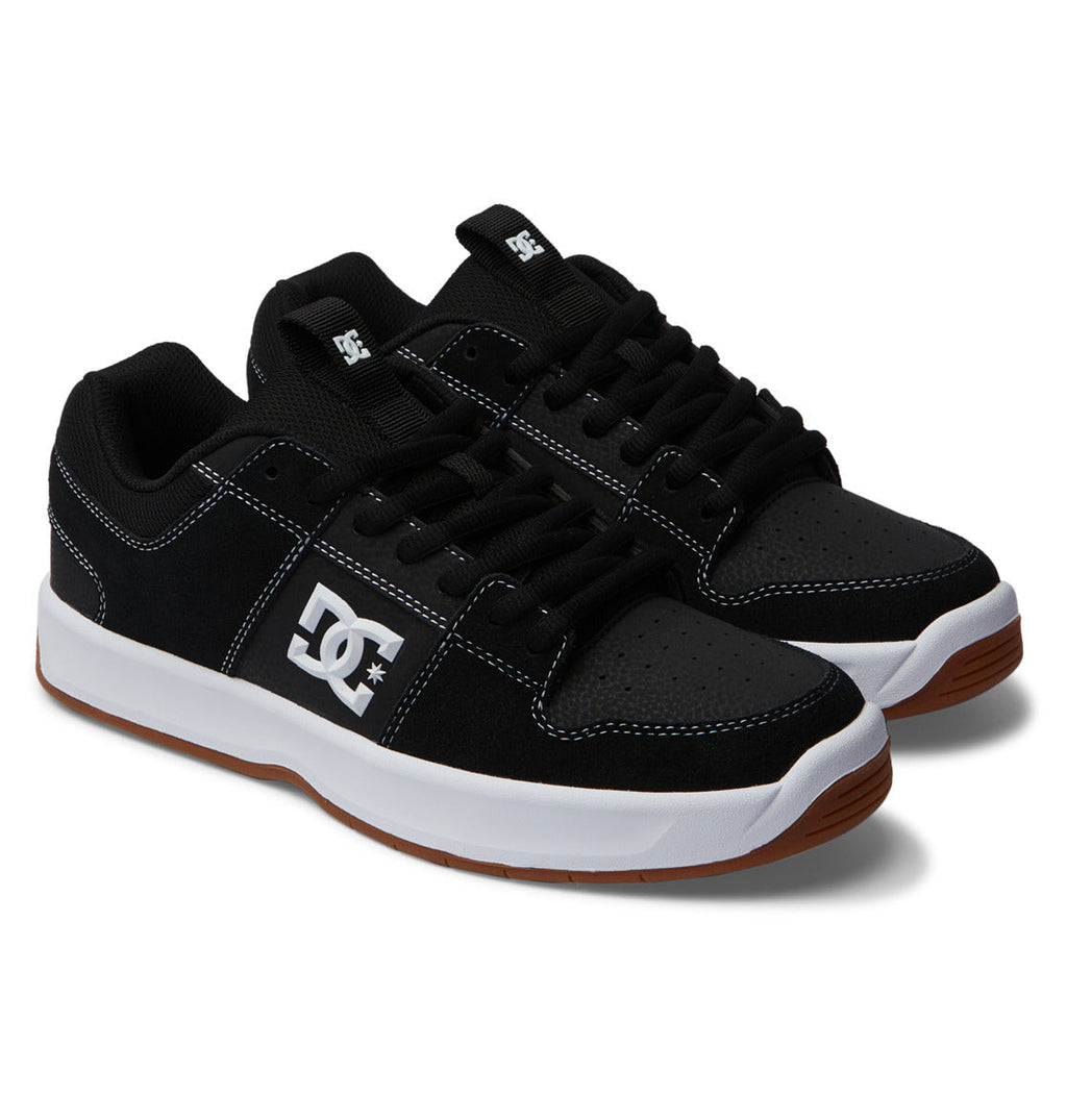 A pair of Men’s Lynx Zero Shoes by DC Shoes in classic black, featuring white stitching, white midsoles, brown gum outsoles, and the signature DC logo on the side—ideal for fans of timeless skate footwear.