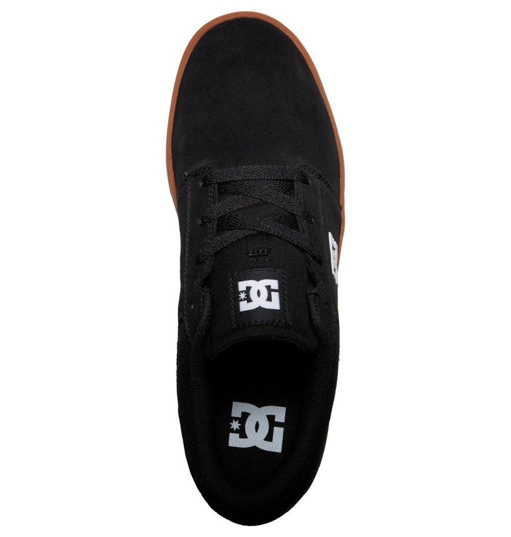 Top view of the Men’s Crisis 2 Shoes from DC Shoes, showcasing a sleek black suede or canvas upper with matching black laces and the distinctive white DC Shoes logo on both the tongue and insole. Featuring a durable brown performance cup sole that provides excellent grip, these shoes offer outstanding style and quality at an affordable price point, making them an ideal choice for budget-conscious skaters.