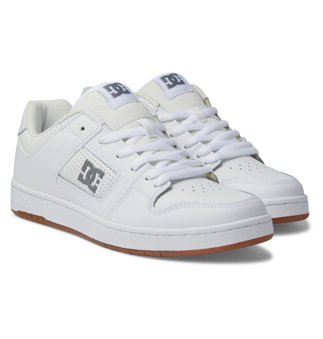 A pair of Men’s Manteca 4 Shoes by DC Shoes in white, featuring white laces, gray DC logos on the side and tongue, perforated side panels, and gum rubber soles, displayed on a white background.