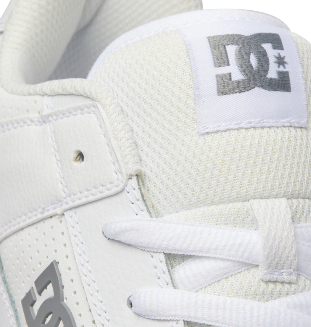 Close-up of a Men’s Manteca 4 Shoe by DC Shoes, featuring the white upper with a gray DC Shoes logo on the tongue, white laces, and textured leather accents—showcasing its classic skate shoe design.