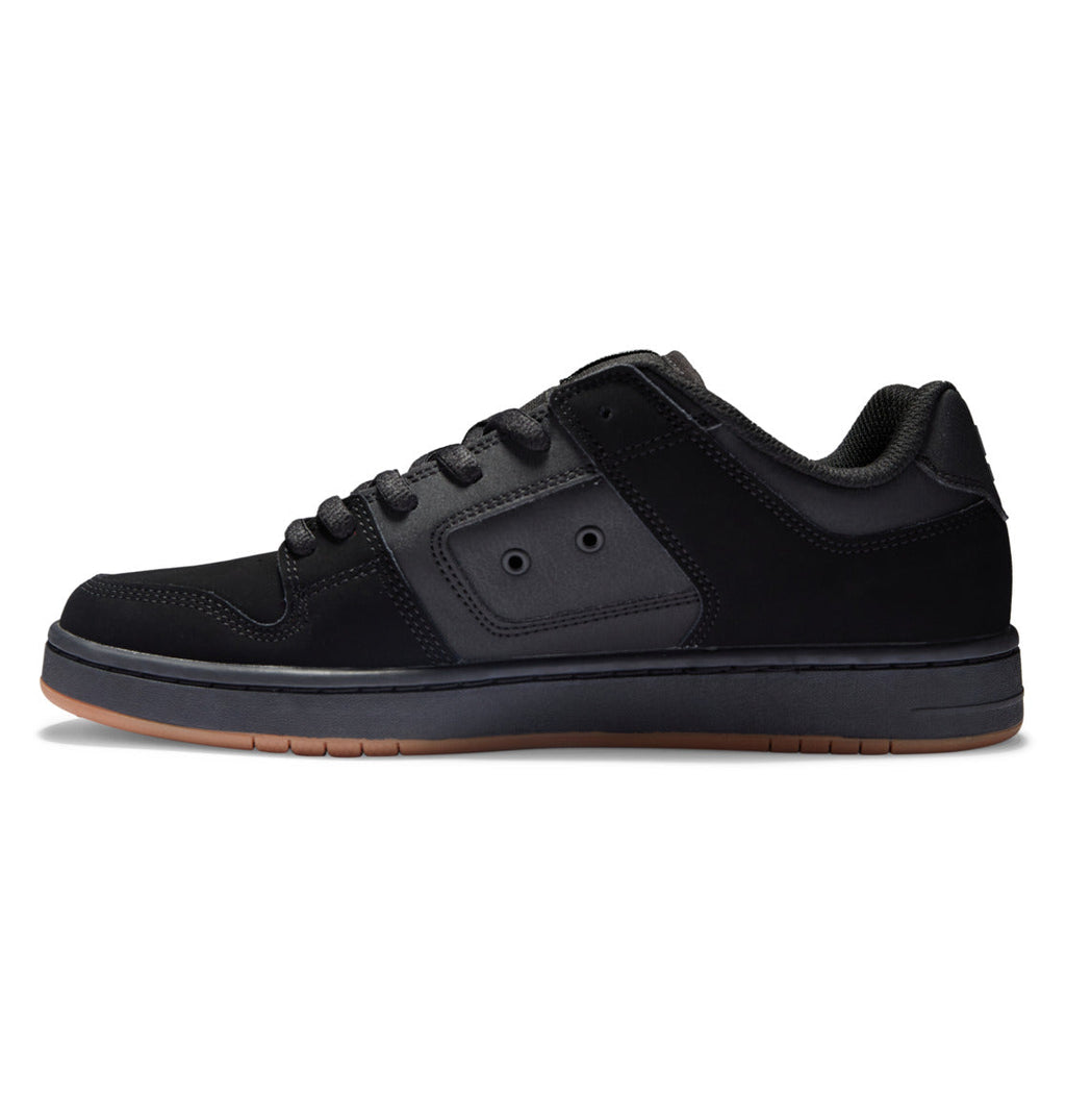 The DC Shoes Men’s Manteca 4 Shoes are black low-top skate shoes featuring black laces, a matching black sole, subtle stitching details, and a brown rubber outsole. Shown in a side profile against a white background, they deliver modern comfort and style.