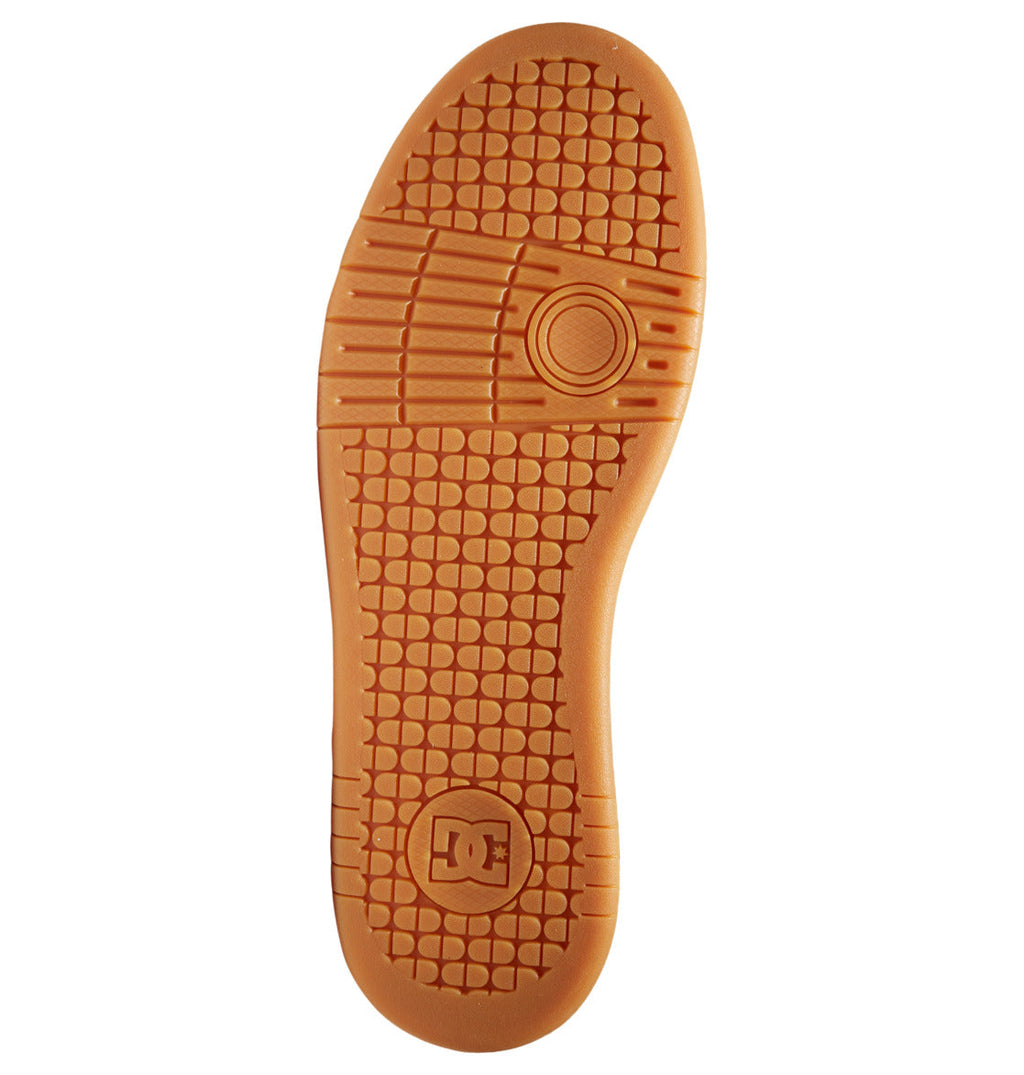 The image displays the sole of the Men’s Manteca 4 Skate Shoes by DC Shoes, featuring a textured orange-brown rubber surface and an engraved DC Shoes logo near the heel, emphasizing its durable cupsole construction for long-lasting wear.
