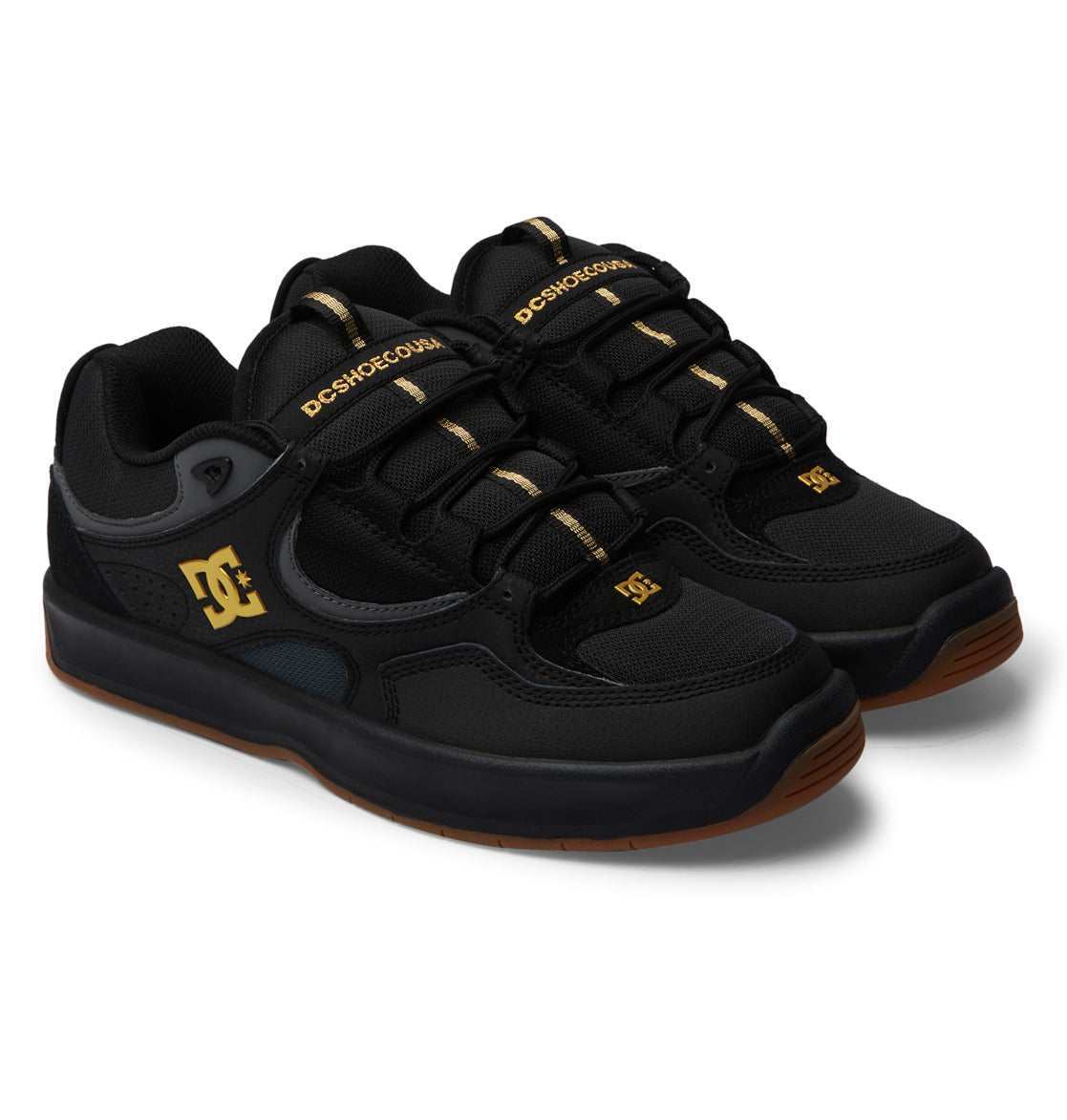 A pair of DC Shoes Men’s Kalynx Zero sneakers in black with gold accents, featuring black laces and brown rubber soles, displayed on a white background.