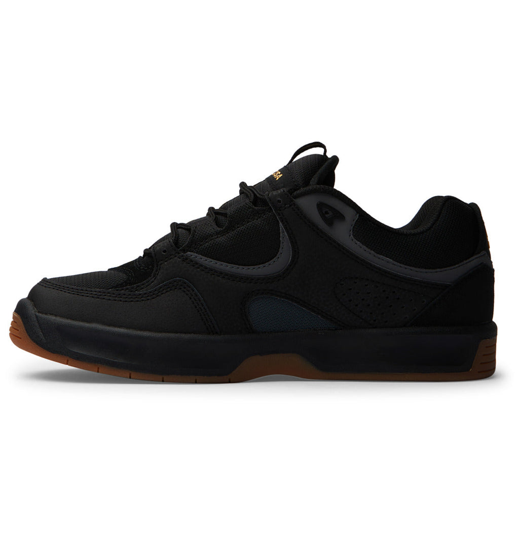 A black, low-profile athletic sneaker—the Men’s Kalynx Zero Shoes by DC Shoes—features mesh and leather accents, black laces, and a brown rubber sole. Shown in profile against a white background.