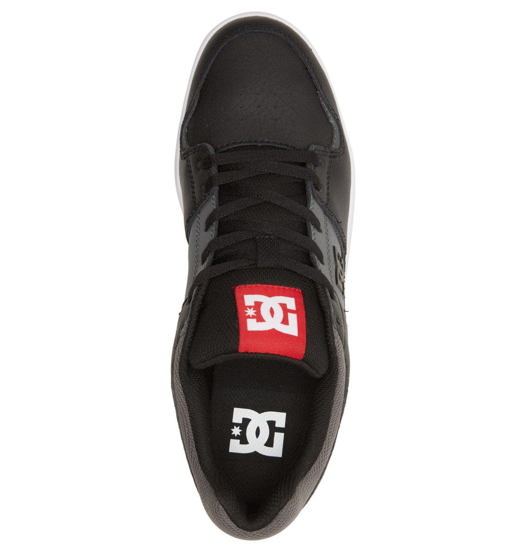 A top-down view of the Men’s DC Cure Shoes by DC Shoes in black highlights the black laces and a red tongue label adorned with the white DC logo. Constructed from durable leather nubuck for long-lasting comfort, these everyday sneakers also feature the signature white DC logo on their black insole.