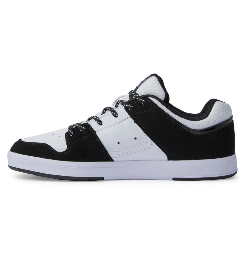 A black and white low-top sneaker from DC Shoes, the men’s DC Cure Shoes feature a durable leather upper with a white side panel accented by small ventilation holes for breathability. The design includes a white sole, black laces, and black detailing around the heel, toe, and lace area—making these classic sneakers perfect for everyday wear.