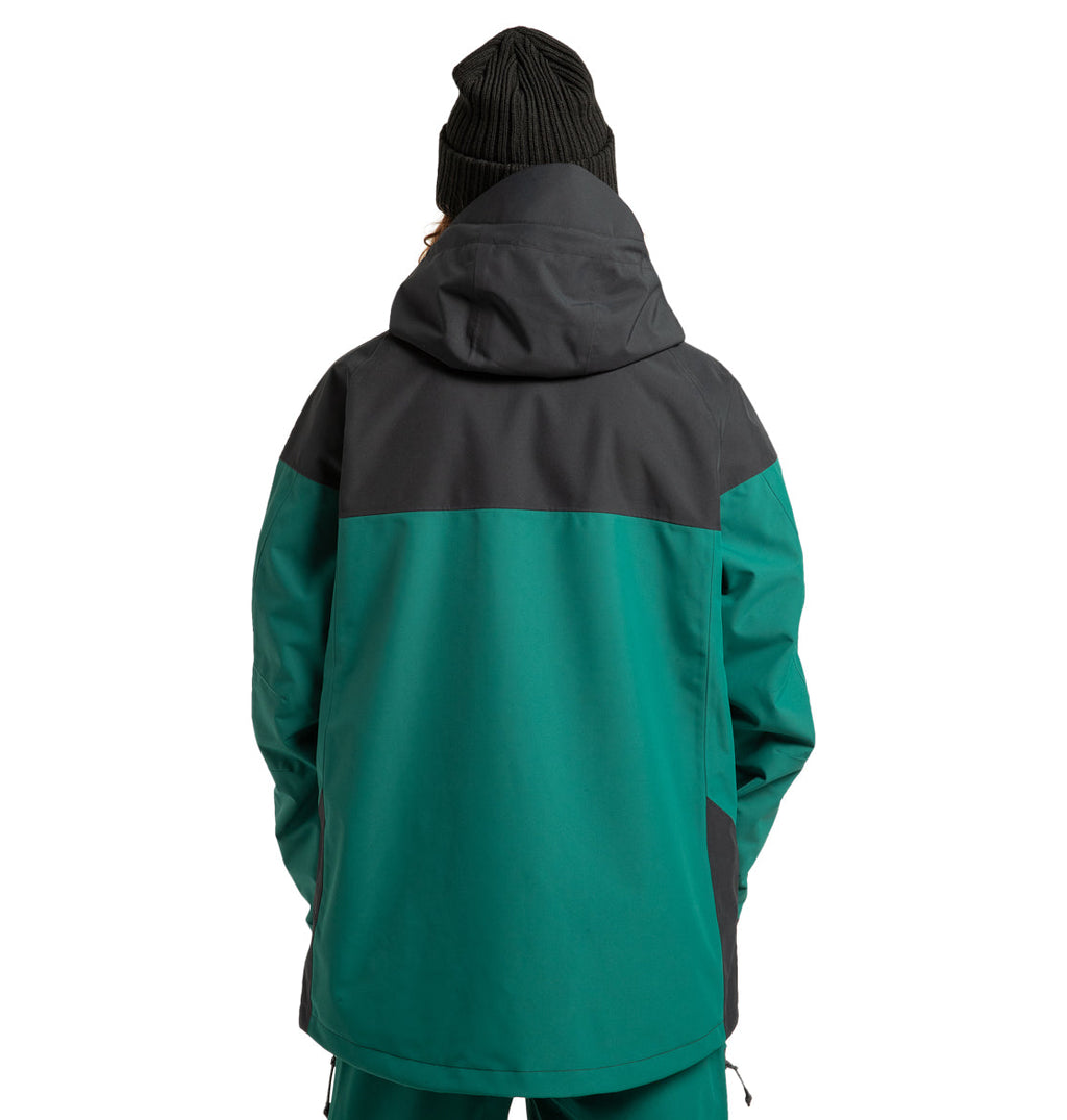 A person wearing the DC Shoes Unisex Intel 30K Insulated Jacket in green and black, designed for adventure and weather resistance, along with a black knit beanie, stands facing away from the camera to showcase the back of the outfit.