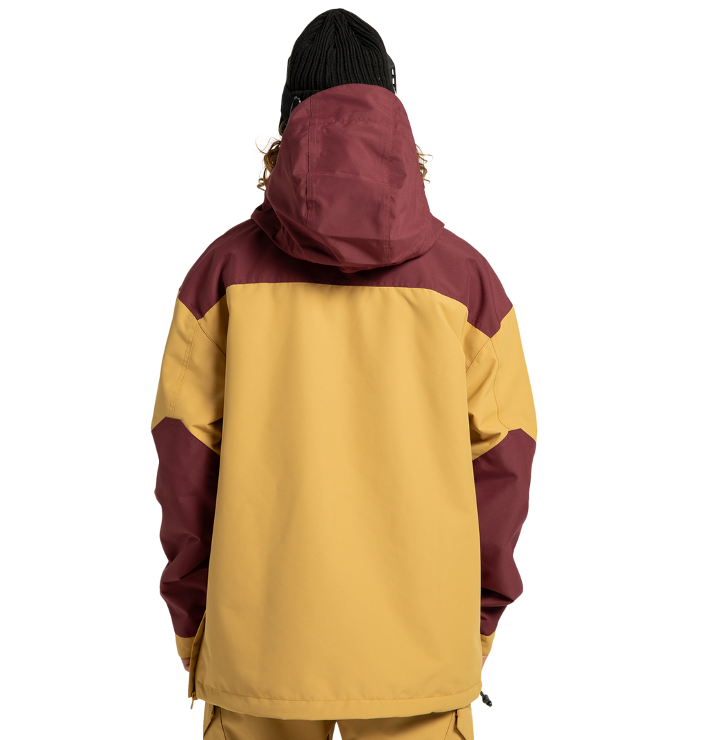 A person stands with their back to the camera against a plain white background, wearing the DC Shoes Men’s DC-43 Anorak Shell Jacket in yellow and maroon with a hood and matching pants. They also have on a black knit beanie.
