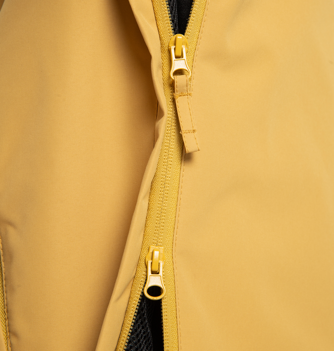 Close-up of the Men’s DC-43 Anorak Shell Jacket by DC Shoes in yellow recycled polyester, featuring two parallel zippers—one partially zipped and the other fully unzipped—to reveal a glimpse of black mesh lining underneath.